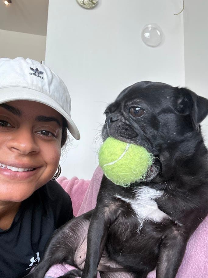 Bianca smiling with a black pug
